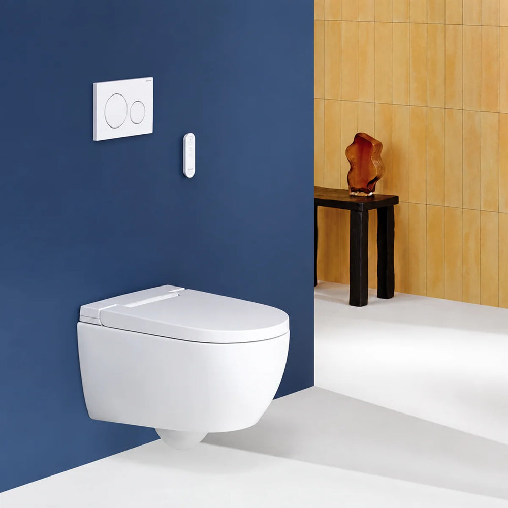 Geberit AquaClean Alba wall-hung WC in white, installed against a navy blue wall with flush plate