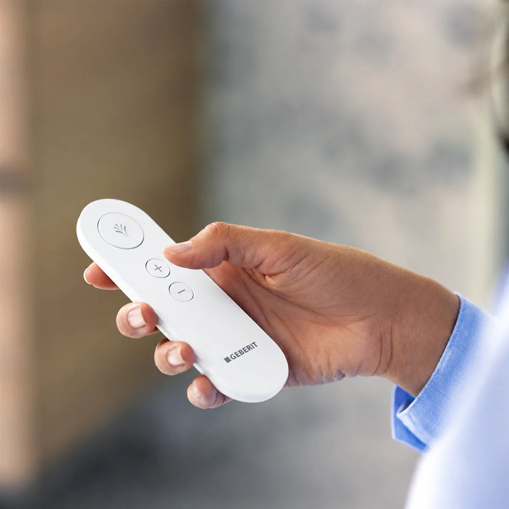 Geberit AquaClean remote control handset in white, held in a person's hand
