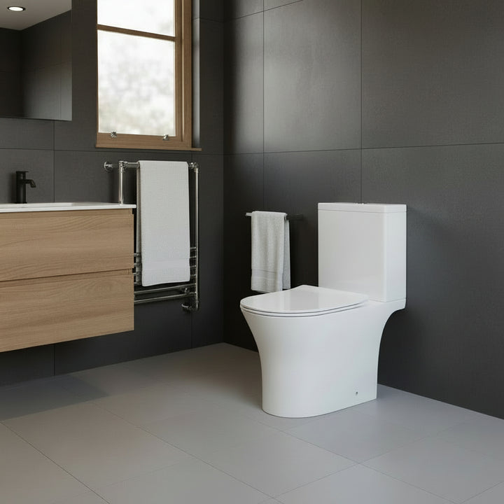 Modern bathroom with a white toilet, wooden vanity, and dark tiled walls.