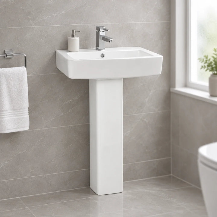 Moods Cassia white ceramic basin and full pedestal with chrome mixer tap, shown in a bathroom with grey marble-effect tiles