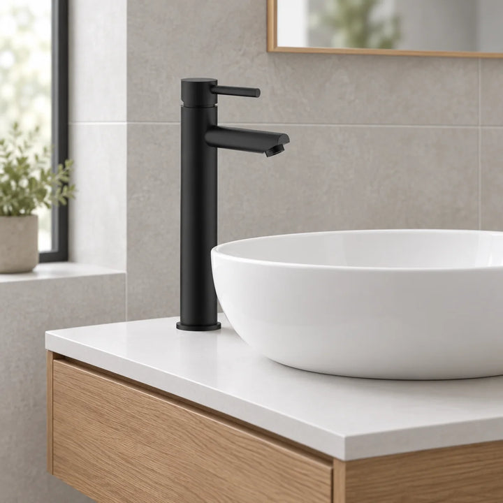 Eliseo Ricci Curve tall black mono basin mixer beside a round white countertop basin on an oak vanity unit with grey tiles