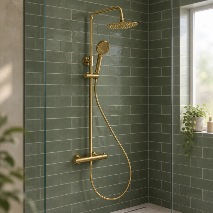 Rotunda brushed brass thermostatic shower set with round rainfall head and handset, mounted on green metro tiles in a glass-screened shower