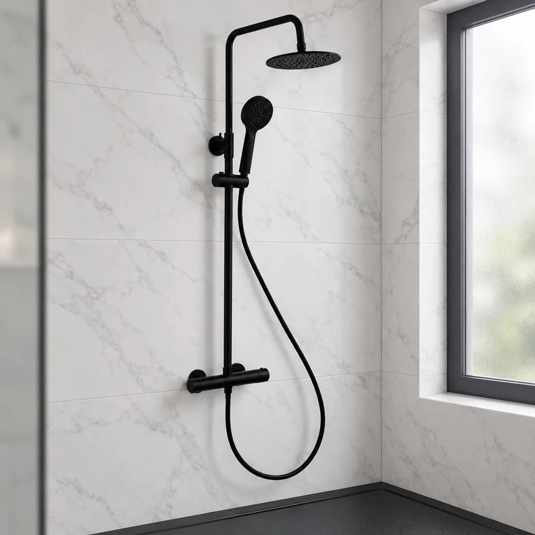 Rotunda round matt black thermostatic shower set with rainfall head and handset, installed on white marble-effect tiles beside a window