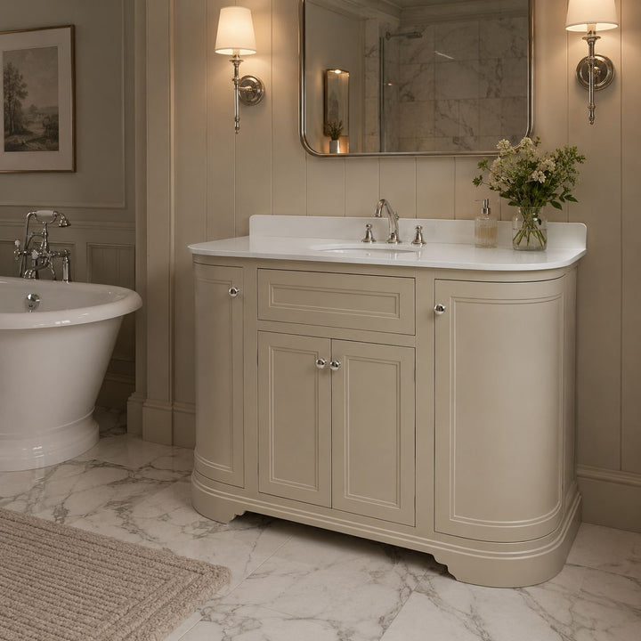 A Traditional floor standing bathroom vanity cabinet with a curved white countertop and integrated basin. The cabinet has a warm sand finish with silver knobs.