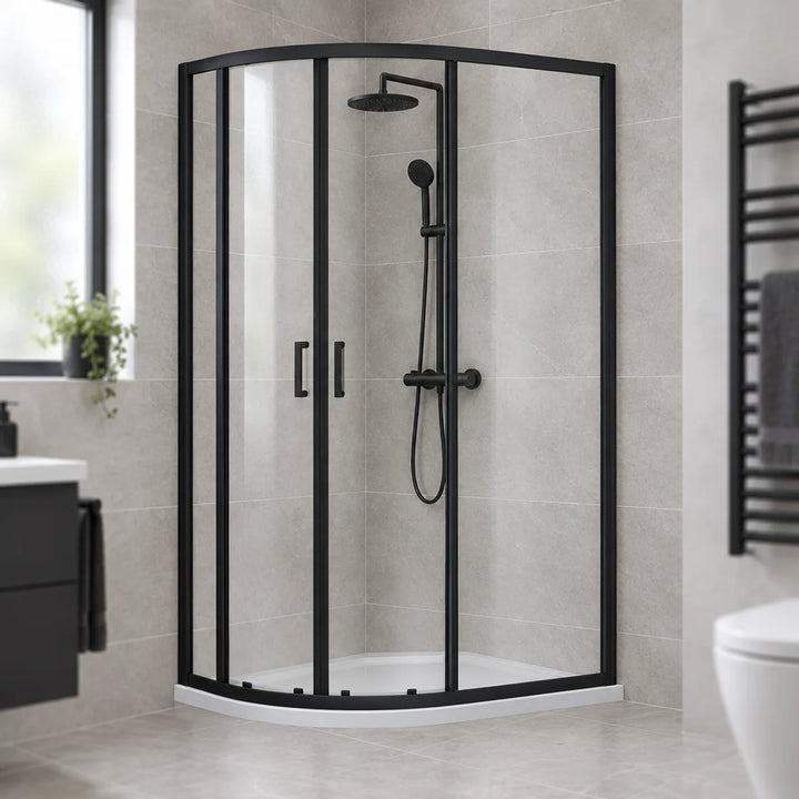 Dene matt black offset quadrant shower enclosure with sliding glass doors in a grey tiled bathroom with black heated towel rail