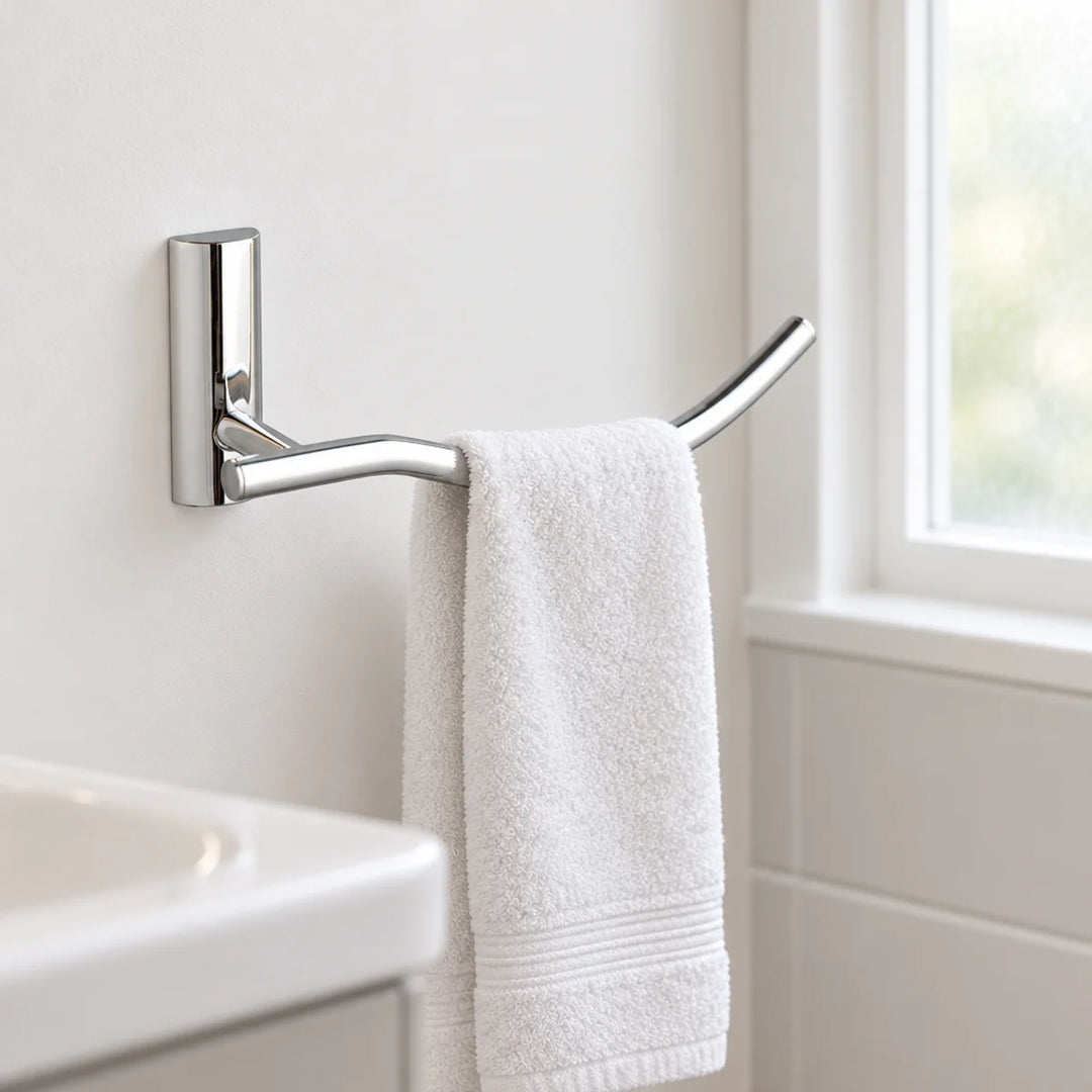 Tre Mercati Twiggy towel ring in polished chrome with a curved bar, holding a white hand towel on a bathroom wall beside a window