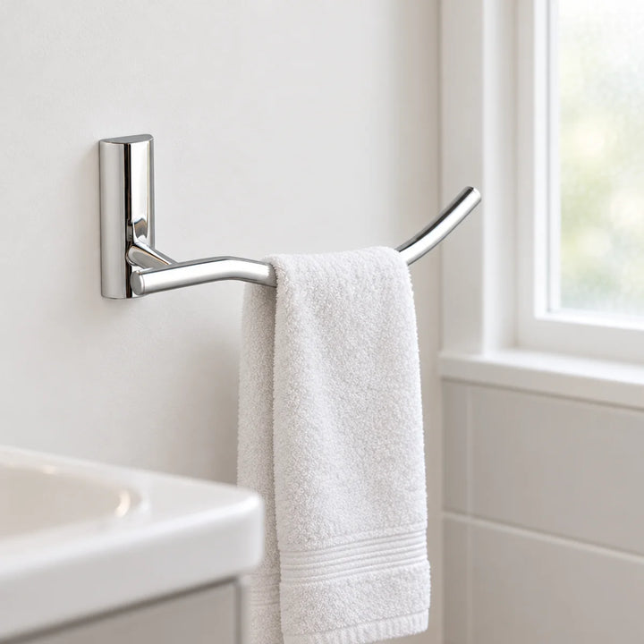 Tre Mercati Twiggy towel ring in polished chrome with a curved bar, holding a white hand towel on a bathroom wall beside a window