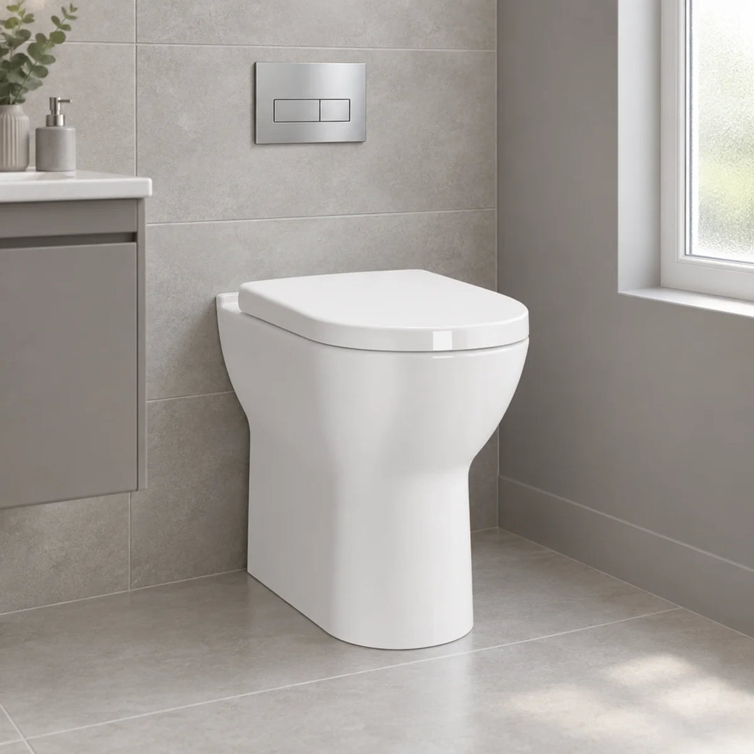 Vitra S50 comfort height back to wall toilet in white with seat, shown in a grey tiled bathroom with chrome flush plate above
